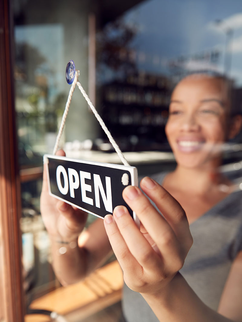 Women at small business with open sign